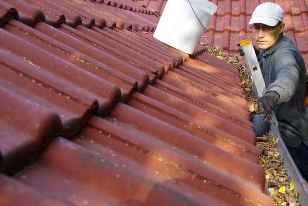 man cleaning roof gutters